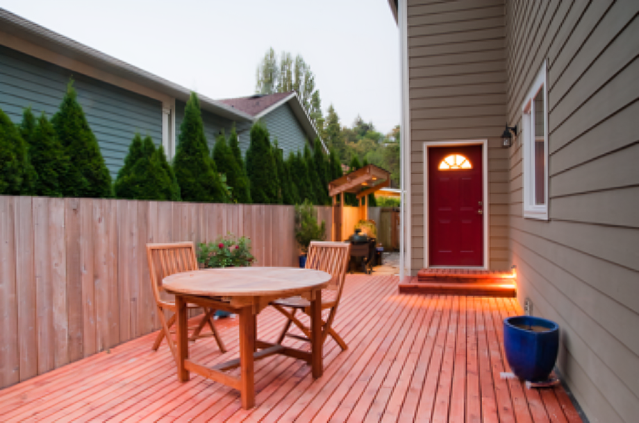 Wooden deck with table, chairs, red door.