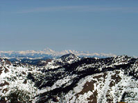 Snowy mountain range under clear blue sky.