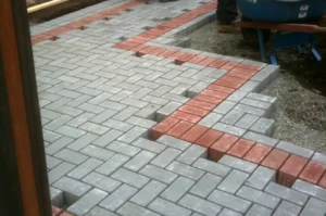 Gray and red brick patio under construction.
