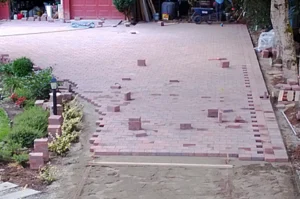 Brick driveway under construction with scattered bricks.