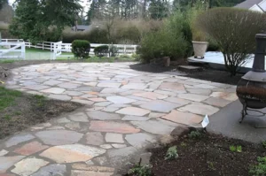 Stone patio with surrounding greenery and trees.