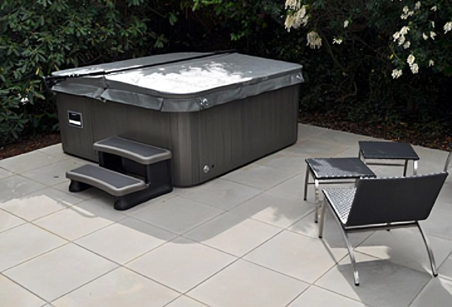 Covered hot tub with chairs on patio.