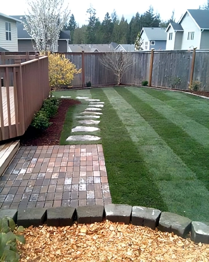 Backyard with grass, stepping stones, and deck.