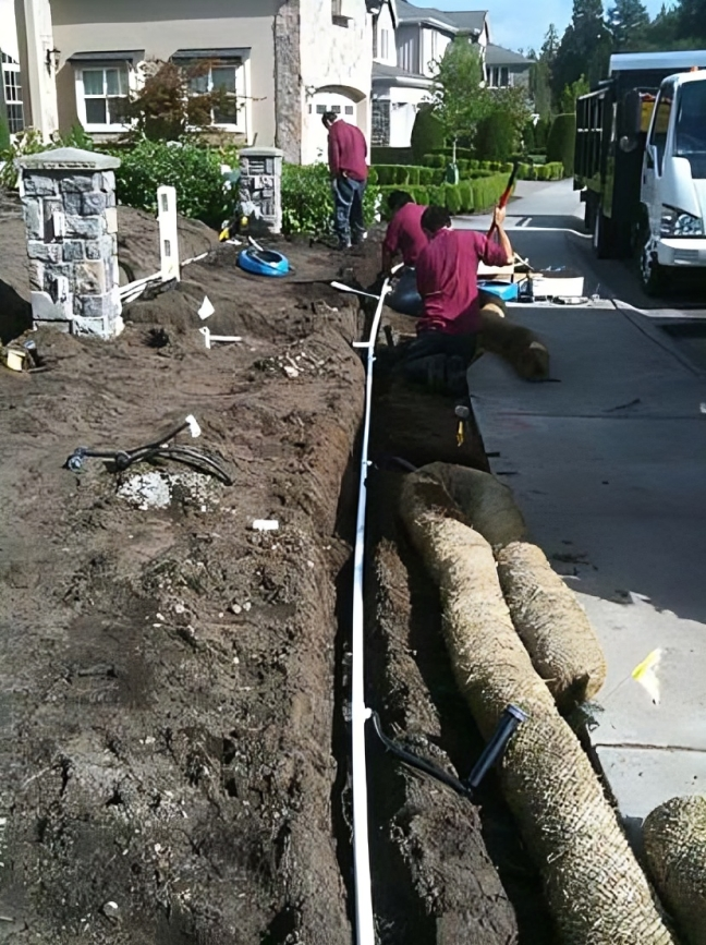 Workers installing pipes in residential landscaping project.