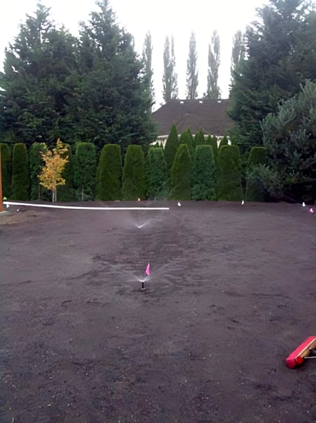 Sprinkler watering a freshly prepared garden area.
