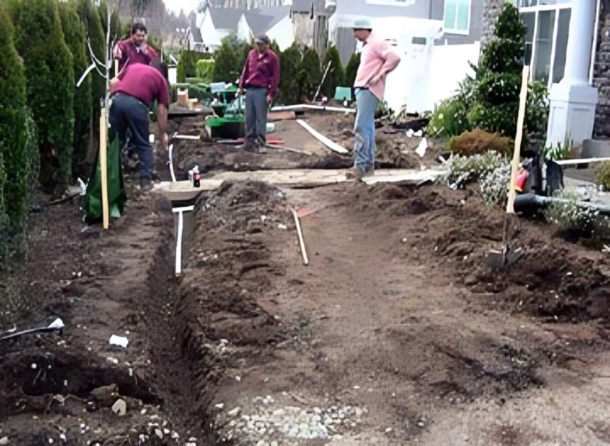 Workers constructing a garden pathway outdoors.