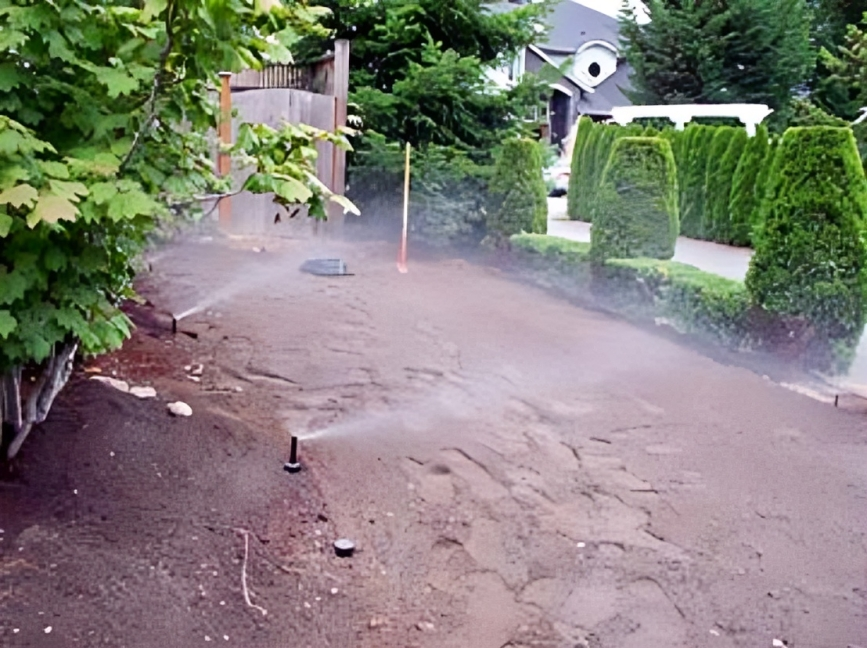 Sprinklers watering soil in residential backyard.