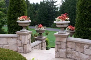 Stone railing with flower planters and greenery.