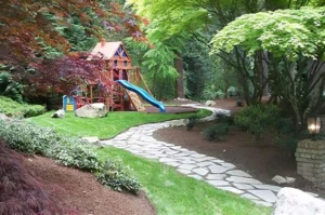 Garden playground with slide and stone path.