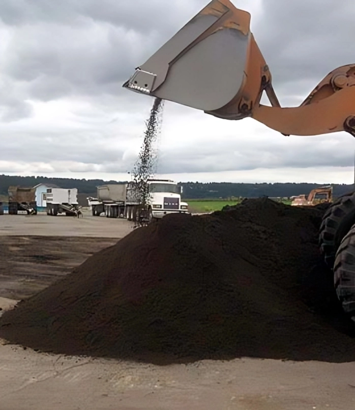 Excavator pouring soil onto large pile.
