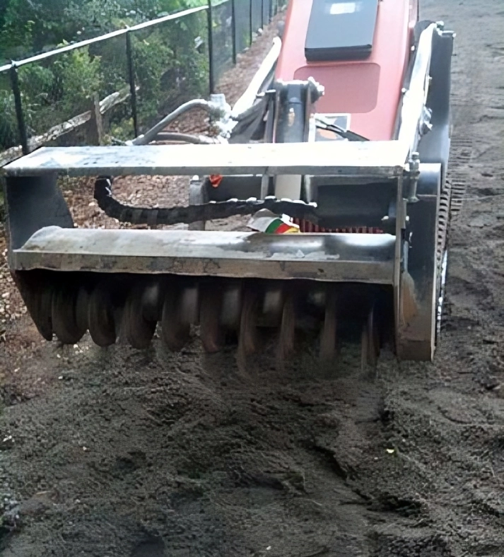 Construction vehicle leveling dirt on a path.